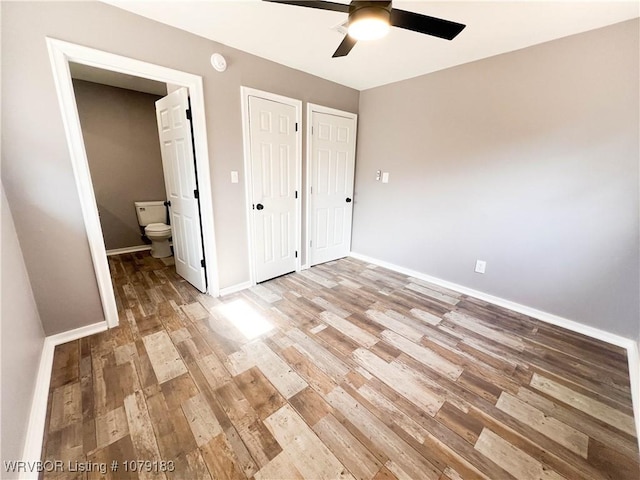 unfurnished bedroom featuring ensuite bathroom, ceiling fan, wood finished floors, and baseboards