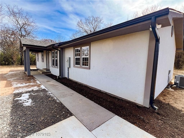 view of home's exterior featuring a porch, stucco siding, and central AC unit