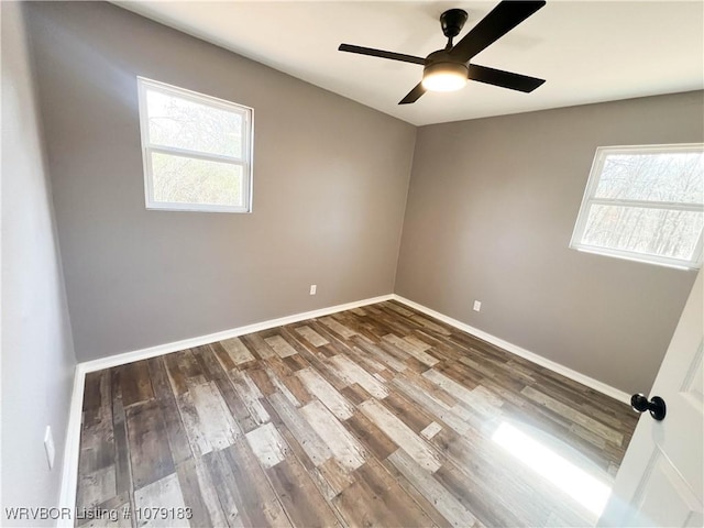 spare room with ceiling fan, dark wood finished floors, a wealth of natural light, and baseboards