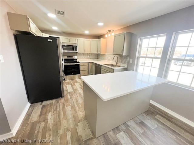 kitchen with visible vents, decorative backsplash, stainless steel appliances, light countertops, and a sink