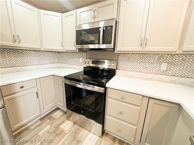 kitchen featuring appliances with stainless steel finishes, light wood-type flooring, backsplash, and light stone countertops