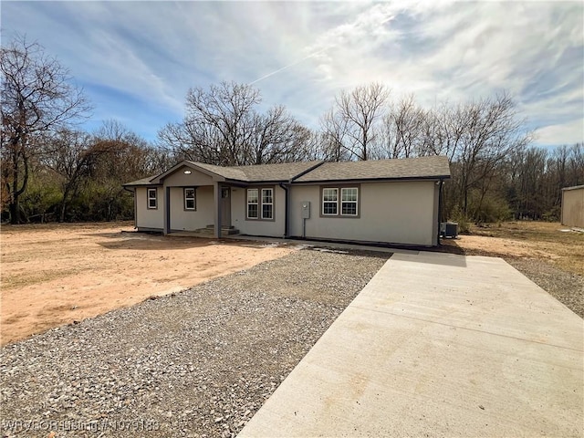 single story home with a shingled roof, central AC, and stucco siding