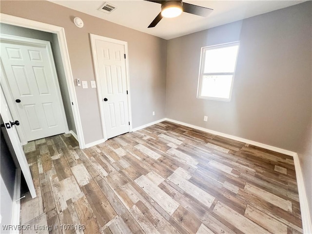 unfurnished room featuring baseboards, a ceiling fan, visible vents, and light wood-style floors