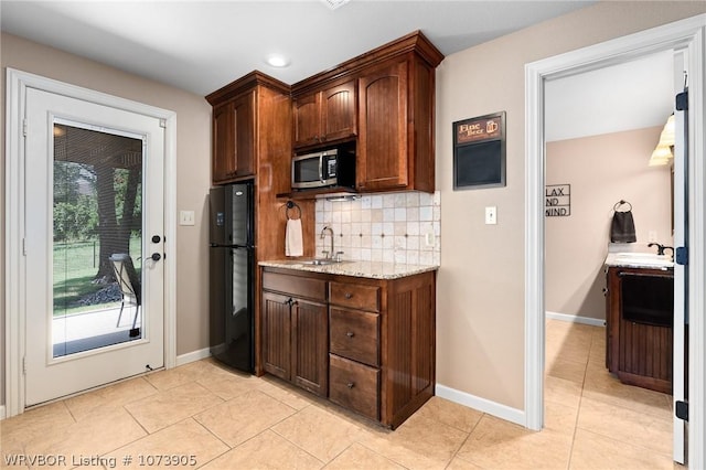 kitchen featuring sink, black fridge, light tile patterned floors, and backsplash