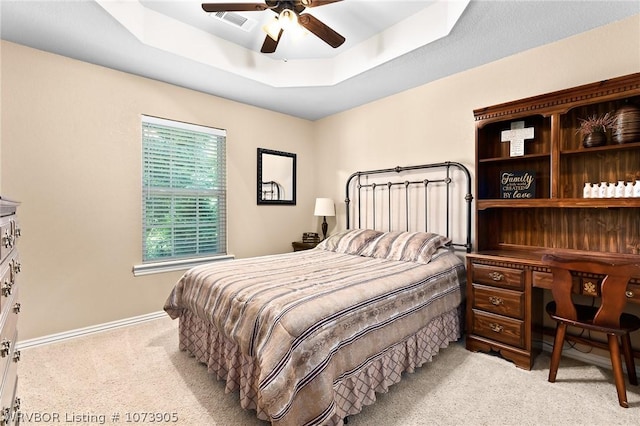 bedroom featuring a raised ceiling, ceiling fan, and light carpet