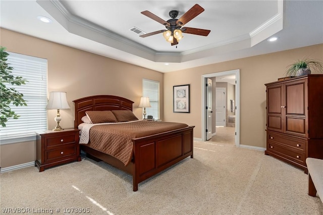 carpeted bedroom featuring a raised ceiling, connected bathroom, ceiling fan, and ornamental molding