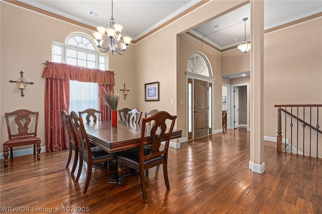 dining space with a towering ceiling, dark hardwood / wood-style floors, an inviting chandelier, and ornamental molding