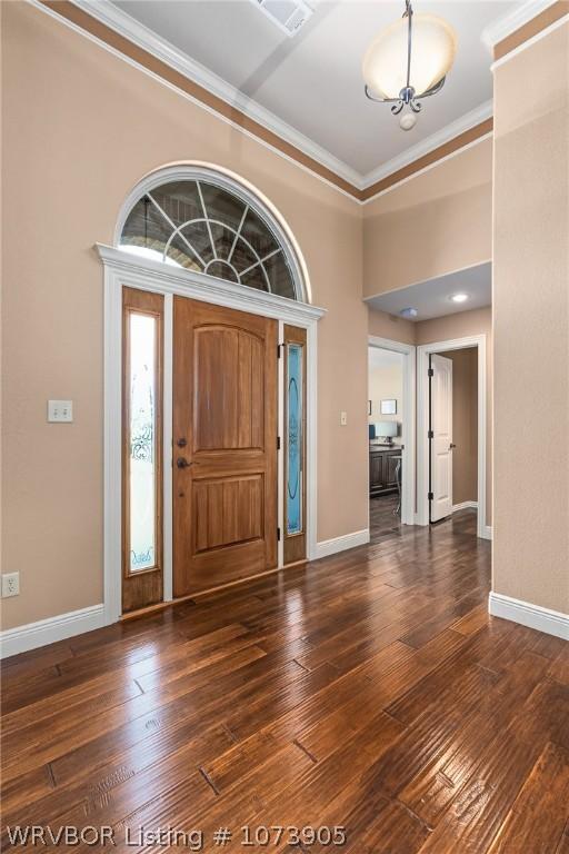 entrance foyer featuring dark wood-type flooring and ornamental molding