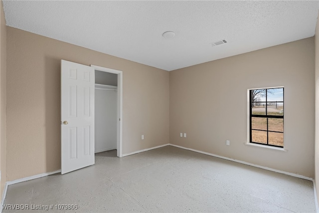 475616 E 1060th Rd, Muldrow, OK 74948 - unfurnished bedroom with baseboards, visible vents, speckled floor, and a textured ceiling