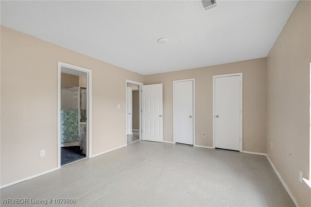 475616 E 1060th Rd, Muldrow, OK 74948 - unfurnished bedroom featuring baseboards, multiple closets, visible vents, and ensuite bath