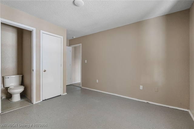 475616 E 1060th Rd, Muldrow, OK 74948 - unfurnished bedroom with connected bathroom, baseboards, and a textured ceiling