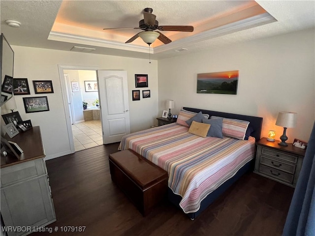 bedroom featuring baseboards, a ceiling fan, wood finished floors, a tray ceiling, and a textured ceiling