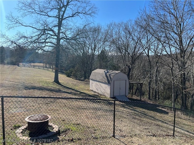 view of yard with a storage shed, an outdoor fire pit, an outdoor structure, and fence