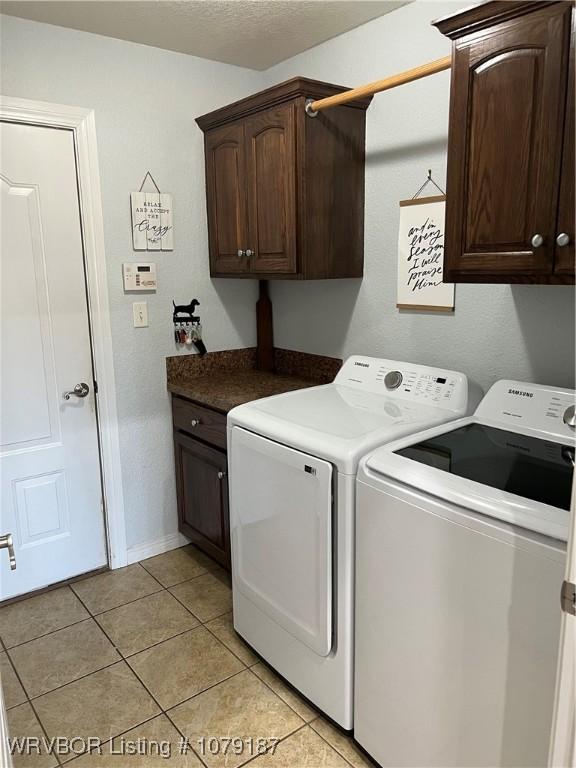 laundry room with washer and dryer, cabinet space, a textured ceiling, and light tile patterned floors