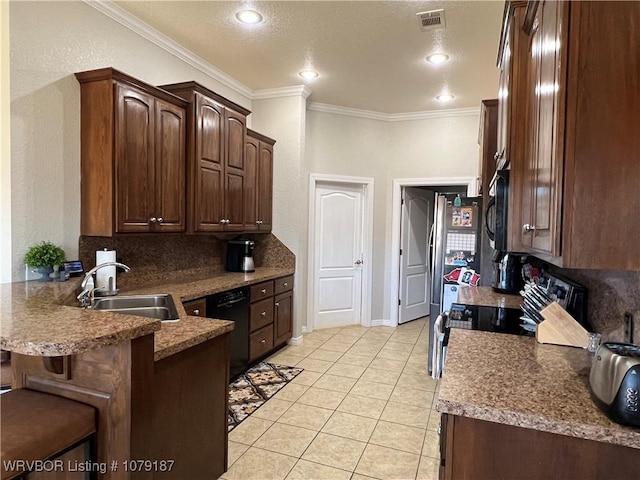 kitchen featuring a breakfast bar area, visible vents, a sink, a peninsula, and black appliances