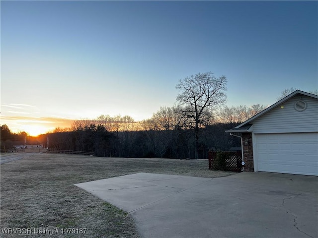 view of yard with a garage and concrete driveway