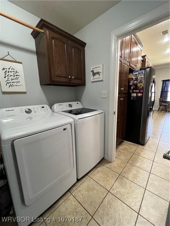 clothes washing area with cabinet space, washing machine and dryer, light tile patterned floors, and visible vents