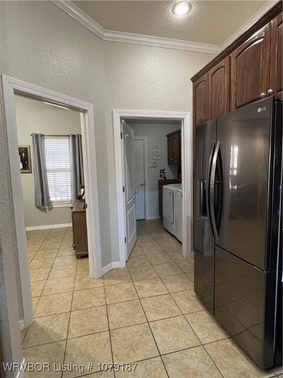 kitchen featuring light tile patterned floors, dark brown cabinetry, black fridge with ice dispenser, washer and clothes dryer, and crown molding