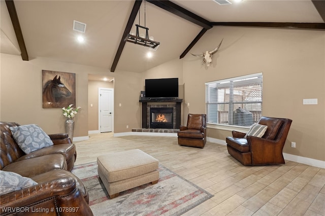 living room featuring high vaulted ceiling, beam ceiling, a tile fireplace, and light wood-type flooring