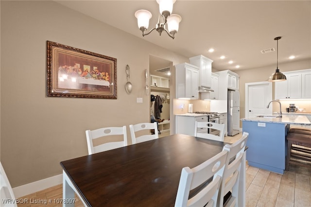 dining room with sink, a notable chandelier, and light hardwood / wood-style flooring