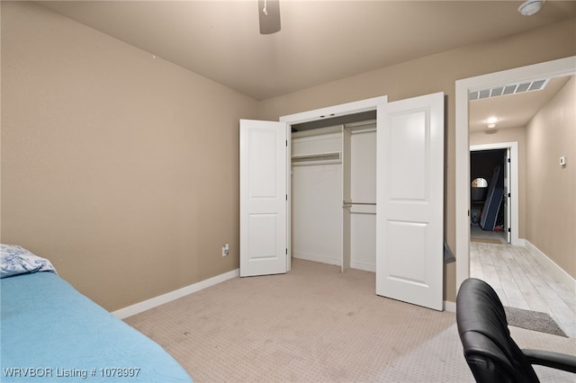 bedroom featuring light colored carpet, ceiling fan, and a closet