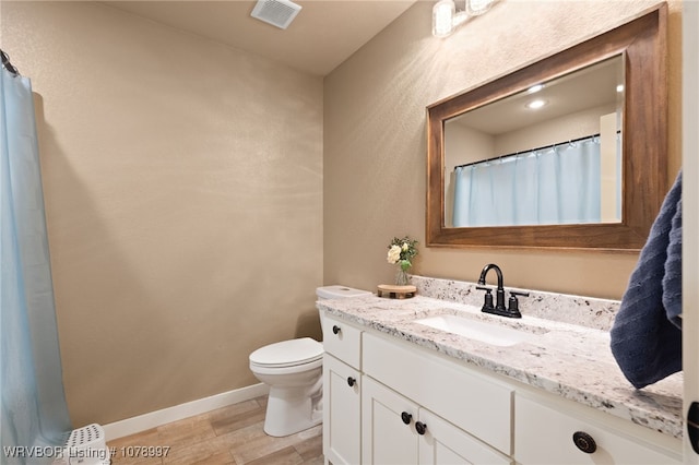 bathroom featuring vanity, hardwood / wood-style flooring, and toilet