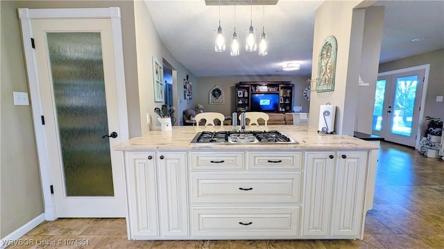 kitchen featuring french doors, decorative light fixtures, light stone counters, kitchen peninsula, and stainless steel gas cooktop