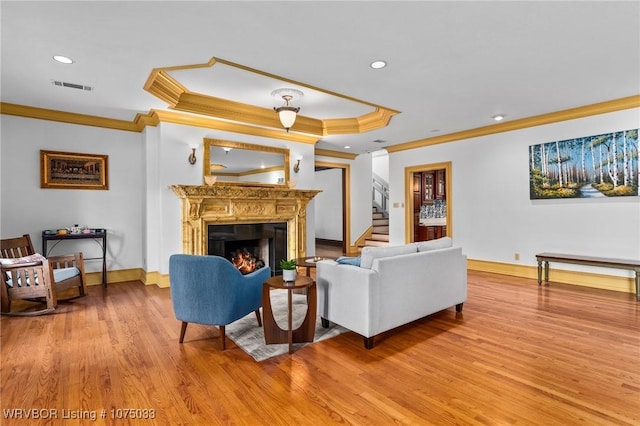 living room with a raised ceiling, crown molding, and light hardwood / wood-style flooring