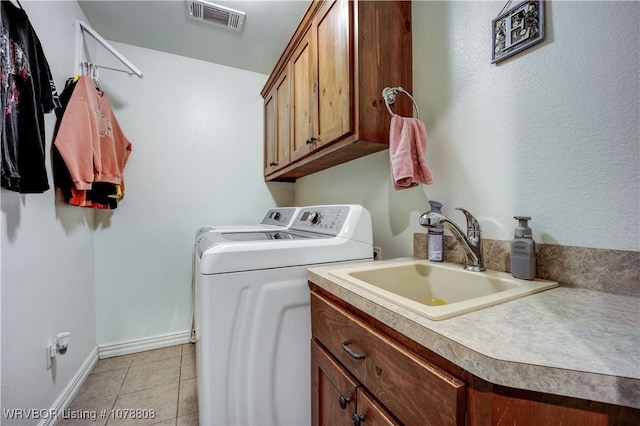 washroom featuring separate washer and dryer, sink, light tile patterned floors, and cabinets