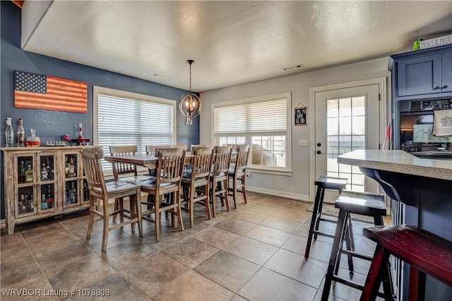 dining area featuring an inviting chandelier, tile patterned floors, and a textured ceiling