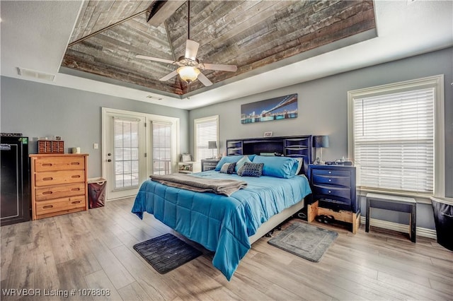 bedroom featuring wood ceiling, light wood-type flooring, a tray ceiling, ceiling fan, and access to exterior