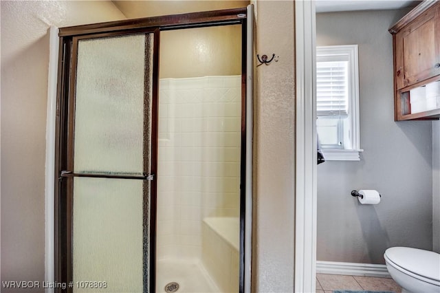 bathroom featuring tile patterned floors, toilet, and walk in shower