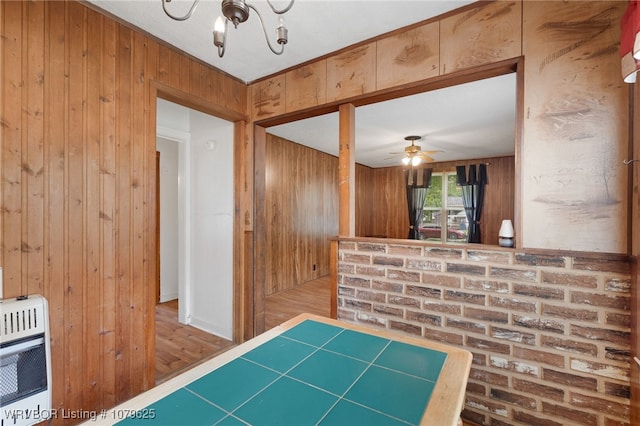 hallway with an inviting chandelier, heating unit, and wood walls