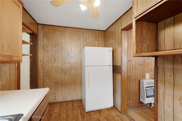 kitchen featuring heating unit, a ceiling fan, light wood-style flooring, freestanding refrigerator, and wood walls