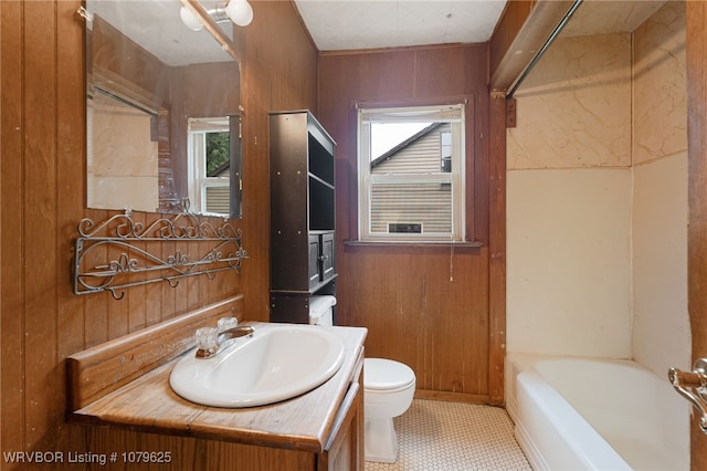 full bathroom featuring vanity, a bathing tub, wood walls, toilet, and a wealth of natural light