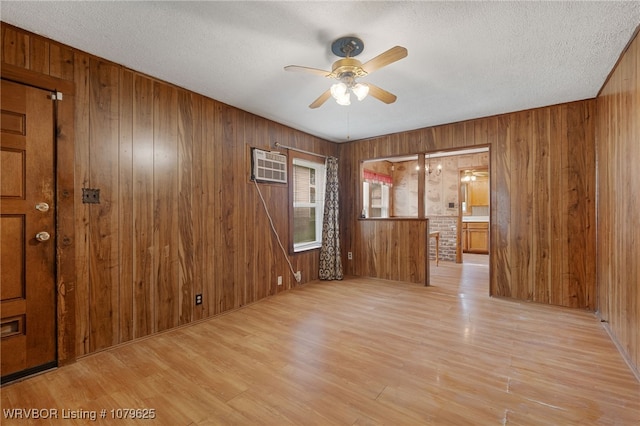 unfurnished room with wood walls, an AC wall unit, ceiling fan, and wood finished floors