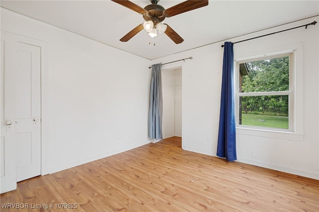 spare room featuring ceiling fan, baseboards, and light wood-style floors