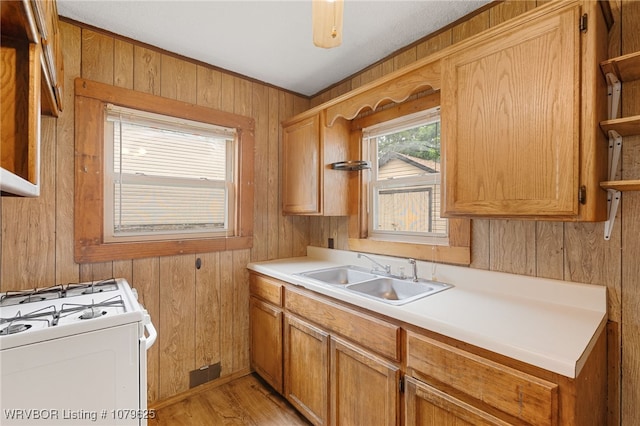 kitchen with a sink, open shelves, wood walls, and white gas range oven