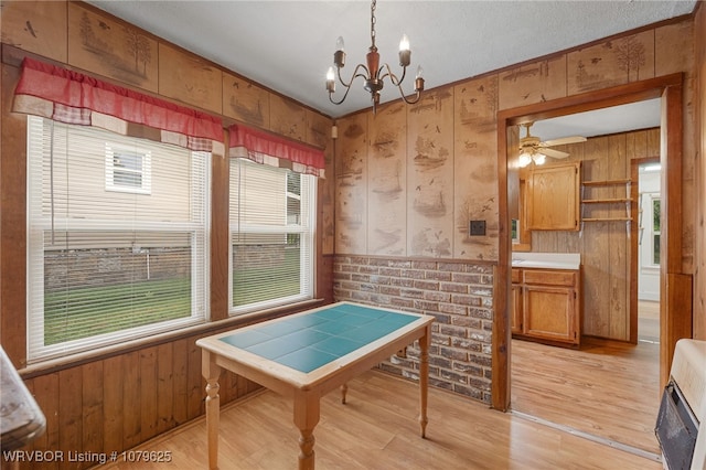 dining space with wood walls, wainscoting, light wood-style floors, heating unit, and a notable chandelier