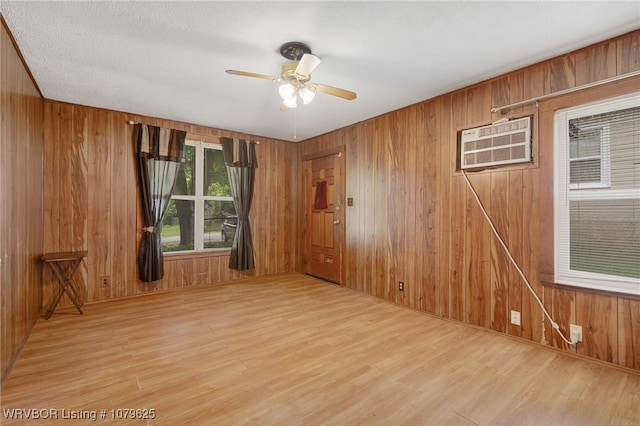 empty room featuring wood walls, a wall mounted AC, ceiling fan, and wood finished floors