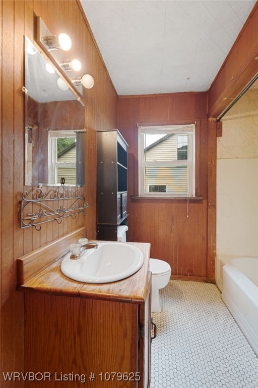 full bathroom featuring a wealth of natural light, wooden walls, vanity, and toilet