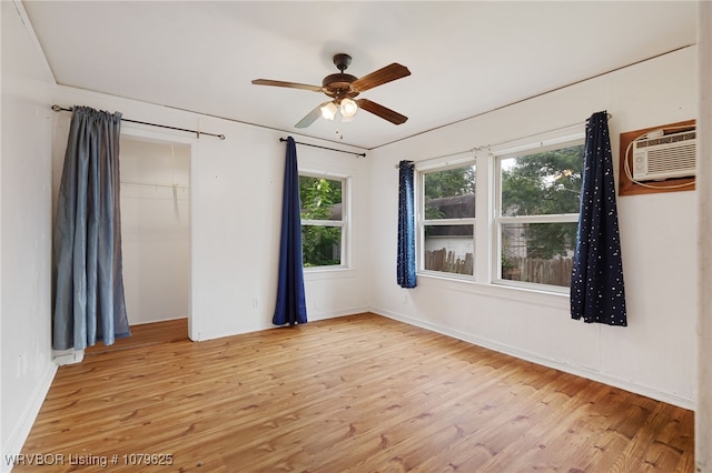 spare room with wood finished floors, a wall mounted air conditioner, and ceiling fan