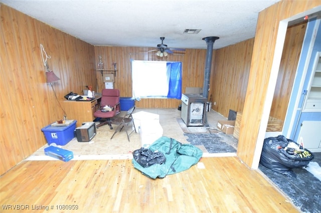1126 S 2nd St, Stilwell, OK 74960 - misc room featuring a wood stove, ceiling fan, wood walls, and wood finished floors