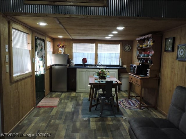 kitchen featuring stainless steel refrigerator, wooden walls, sink, and dark wood-type flooring