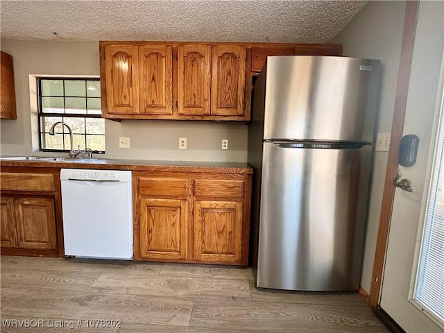 306 Ellis Loop, Pocola, OK 74902 - kitchen with white dishwasher, stainless steel fridge, light wood-type flooring, and sink