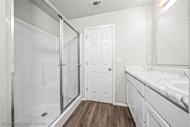 full bathroom with visible vents, a shower stall, wood finished floors, vanity, and baseboards