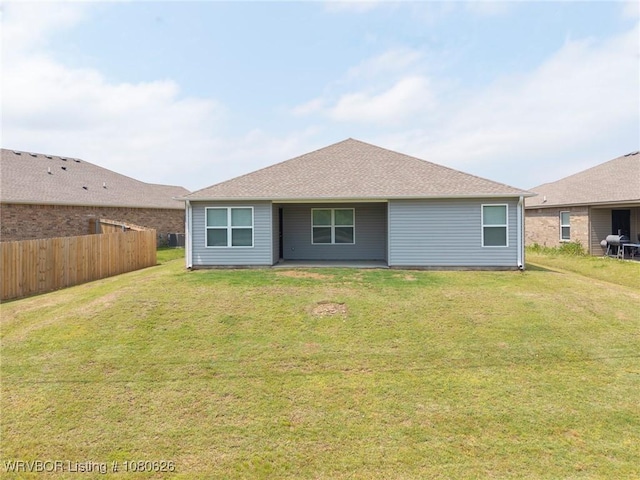 rear view of house with a patio, fence, and a yard