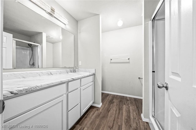 full bathroom with baseboards, a shower with door, vanity, and wood finished floors