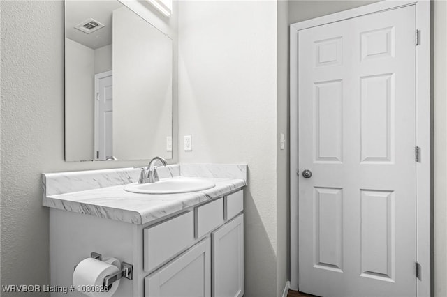 bathroom featuring vanity, a textured wall, and visible vents