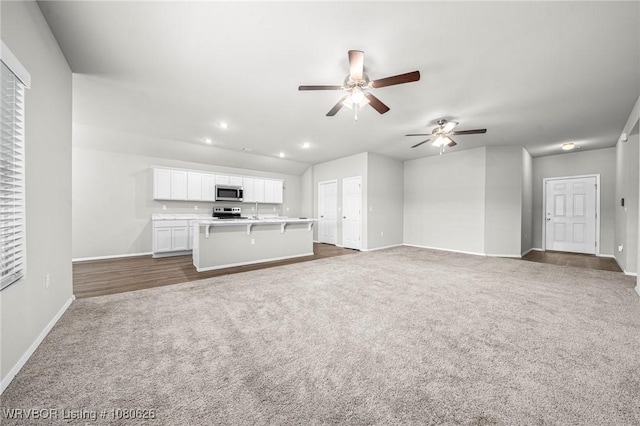 unfurnished living room featuring a ceiling fan, a sink, baseboards, recessed lighting, and dark carpet